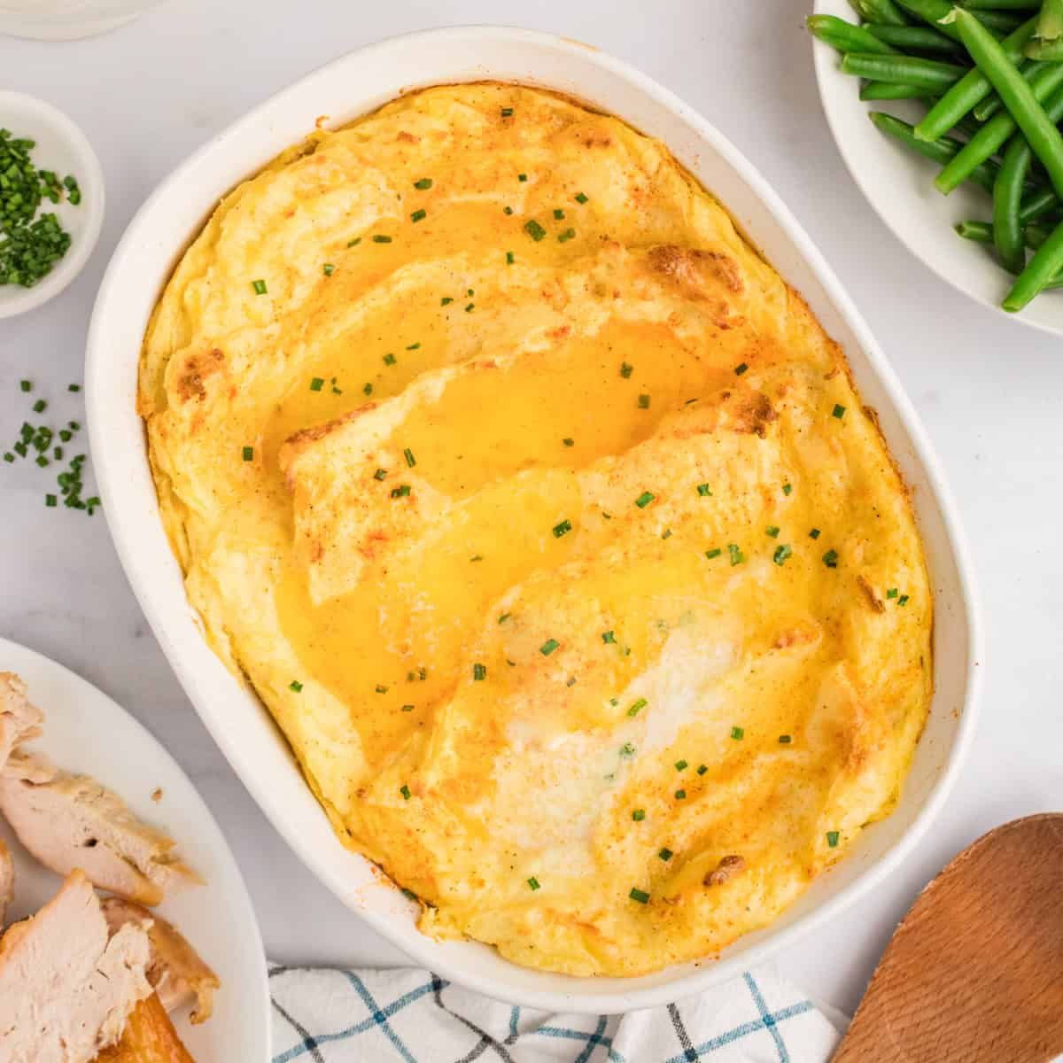 Fluffy baked mashed potatoes in individual ramekins topped with a golden brown cheese crust and fresh chives